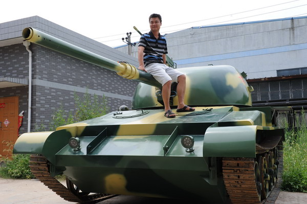 Hao Jinxi, owner of a factory that produces imitation trains, sits on a life-size model of a T-62 tank, his newest product, in Yuhang, Zhejiang province. Getting a 'bang' with his toy